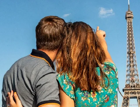 Pareja de espaldas señalando la Torre Eiffel bajo un cielo azul, parte de la velada con entradas Moulin Rouge