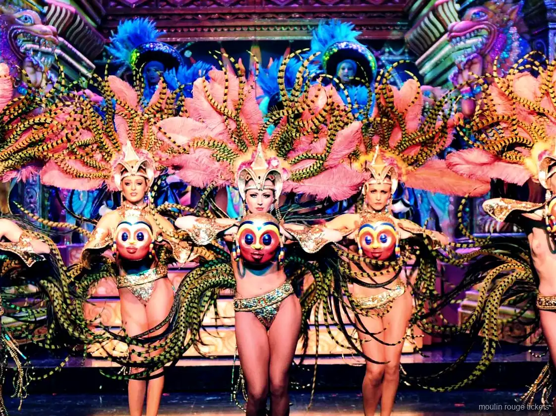 Danseuses aux ailes de plumes roses et rayées, masques dorés, sur un décor orné, dîner spectacle Moulin Rouge