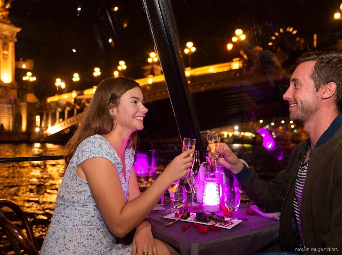 Couple trinquant au champagne lors d'un dîner croisière de nuit sur la Seine, avant le show avec billets Moulin Rouge
