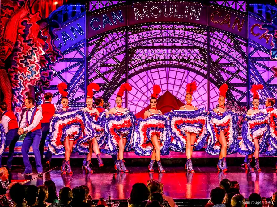 Bailarinas de French cancan com saias de babados sob o letreiro Moulin Can Can, o show dos bilhetes Moulin Rouge