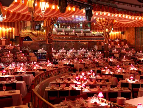 Moulin Rouge biljetter: kabarésalongen med rödrandigt tak, bord i terrasser och rosa bordslampor