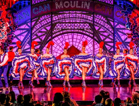 青いフリルスカートで空中開脚を決めるカンカンの踊り子と後ろのパートナー、ムーランルージュ ディナーショー チケットで観る舞台