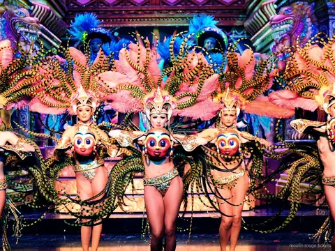 Dancers in pink and striped feather wings with gilded masks on an ornate set, Moulin Rouge dinner show tickets