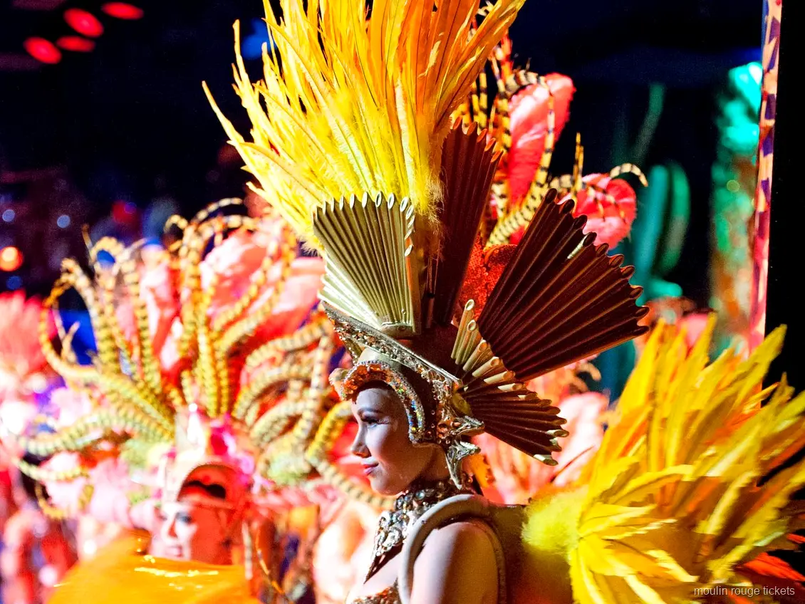 Moulin Rouge Tickets: Tänzerin mit goldenem Federkopfschmuck und Fächerkrone auf der Bühne
