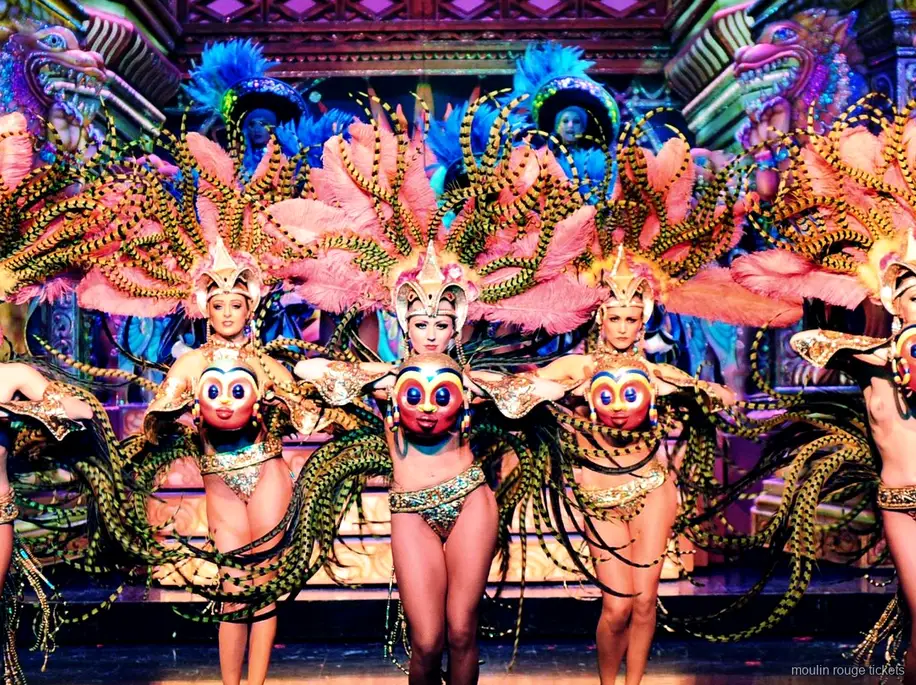 Ballarines amb ales de plomes roses i ratllades i màscares daurades en un decorat ornamentat, sopar Moulin Rouge