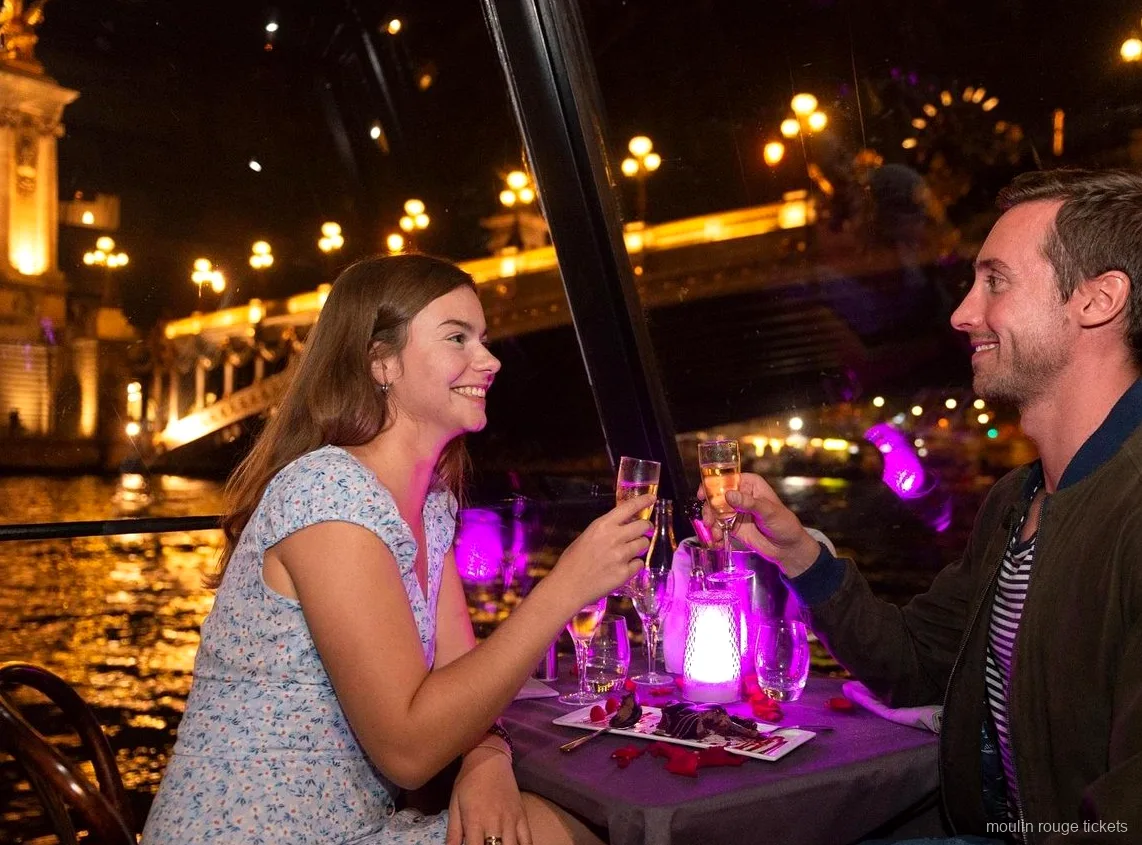 Parella brindant amb xampany en un sopar en creuer pel Sena de nit, abans de les entrades al Moulin Rouge