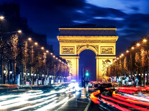 Arco do Triunfo iluminado à noite no fim da Champs Élysées com rastros de luz, roteiro antes dos bilhetes Moulin Rouge